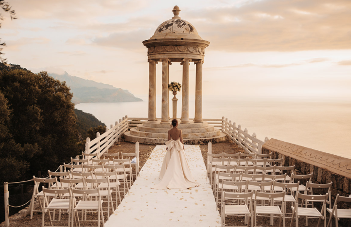 Bride in a white gown at the Son Marroig rotunda overlooking the sea during a Mallorca destination wedding ceremony at sunset
